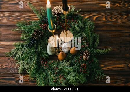 Joyeux Noël. Arbres de Noël et bougies dans une couronne de noël rustique sur bois sombre. Décoration moderne festive. Pins miniatures, bougeoirs et mode Banque D'Images