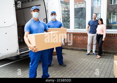 Blue Delivery Men déchargement du paquet du camion avec masque facial Banque D'Images