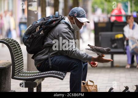 Glasgow, Écosse, Royaume-Uni. 8 juillet 2020. Photo : un homme nourrit les pigeons à la main dans la rue Sauchielhall du quartier commerçant de Glasgows. Crédit : Colin Fisher/Alay Live News Banque D'Images