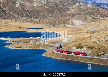 Grisons, Suisse - octobre 21.02018 : le train Bernina se courbe le long du lac glacier Bianco sur le col Bernina. C'est un train classé au patrimoine mondial de l'UNESCO Banque D'Images