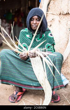 Femme âgée travaillant avec de la paille dans le village de Melabday, Asso Bhole, Dallol, Danakil Dépression, région d'Afar, Ethiopie, Afrique Banque D'Images