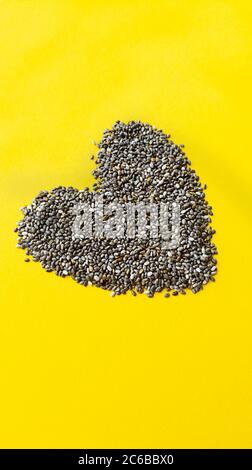Forme du coeur des graines de chia sur fond jaune. Simple, plat, texture pastel. Concept d'alimentation saine. Photo. Banque D'Images