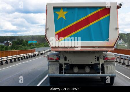 Gros camion avec le drapeau national de la République démocratique du Congo se déplaçant sur la route, sur le fond du village et de la forêt landsca Banque D'Images