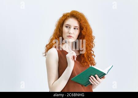 Laissez-moi penser. Une photo studio d'une jolie fille aux cheveux rouges qui regarde sur le côté avec une expression réfléchie et grossière sur son visage, comme si elle avait une bonne idée p Banque D'Images