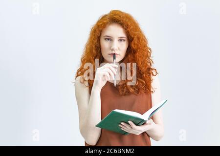 Laissez-moi penser. Une photo studio d'une jolie fille aux cheveux rouges qui regarde sur le côté avec une expression réfléchie et grossière sur son visage, comme si elle avait une bonne idée p Banque D'Images