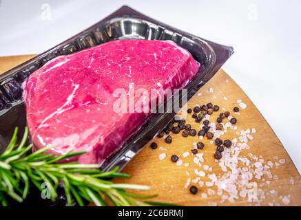 Steak de bœuf emballé sous vide et épices sur planche à découper en bois Banque D'Images