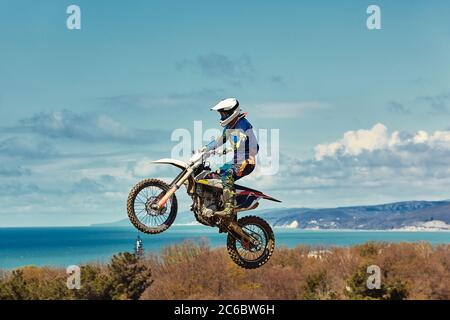 Concept extrême, défiez-vous. Saut extrême sur une moto sur un fond de ciel bleu avec des nuages. Copier l'espace, tout ou rien. Banque D'Images