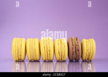 Rangée de macarons colorés parfaits sur fond violet. Vue avant. Banque D'Images