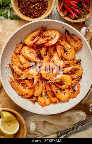 Crevettes grillées sur une poêle à frire servies sur un tableau à découper en bois blanc Banque D'Images