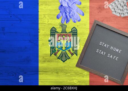 Arrière-plan du drapeau de Moldavie sur une table en bois. Tableau d'écriture de séjour à la maison, gants de chirurgie, pilules avec le concept national minimal Covid 19. Banque D'Images