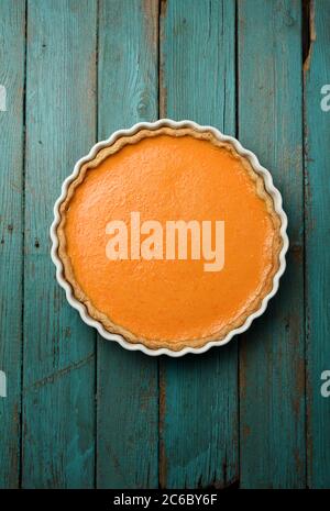 Tarte à la citrouille maison ouverte dans un plat blanc sur un plateau en bois turquoise et en bois, vue sur le dessus de l'espace de copie Banque D'Images