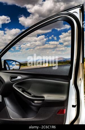 27 juin 2013, Santa Fe, Nouveau Mexique, États-Unis: Nouveau Mexique Nord au Colorado sur l'autoroute 284 Nord une vue des nuages, ciel bleu, route ouverte dans les montagnes au loin, vu à travers la voiture de passager fenêtre avec la porte ouverte charpente la vision de l'Ouest américain. Suzanne Krieger femme qui vit à New York depuis 1924, se Marie, devient mère de 3 garçons et est artiste, réalise dans ses années 80 qu'elle ne peut plus vivre seule. Suzanne Krieger est sur le point de voyager de la côte est de New York à l'Ouest américain au Colorado (USA), pour devenir résidente permanente au Veterans CEN Banque D'Images