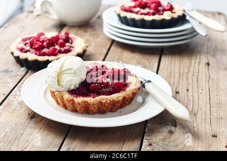 Mini-tartes cuites aux framboises sur une table rustique en bois. Banque D'Images