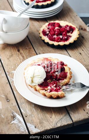 Mini-chaussons cuits aux framboises sur une table rustique en bois. Banque D'Images