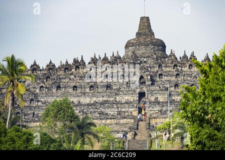 Certains touristes grimpent le temple de Borobudur pendant une journée ensoleillée. Central Java, Indonésie. Banque D'Images