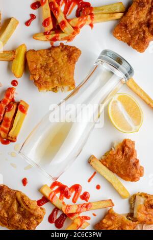 Verre de bière vide tombé parmi les poissons et les frites Banque D'Images