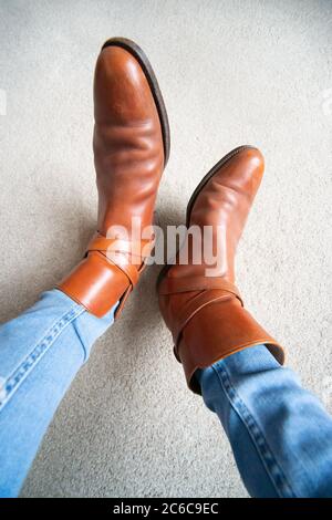 Bottes brunes avec boucle portées sur un Jean bleu. Un style similaire à celui des bottes chelsea ou Cowboy. Mode, style, tendance, vintage. Banque D'Images