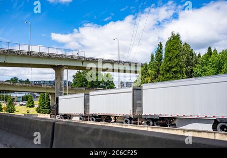 Cabine brune de jour, grand semi-camion pour les voyageurs d'affaires transportant des marchandises commerciales dans trois semi-remorques de train routier couplées allant sous les plusieurs Banque D'Images