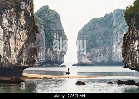 Homme pêche sur un bateau dans la baie de halong Banque D'Images