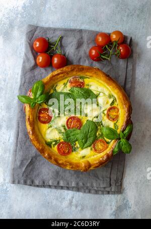 Tarte ou quiche française végétarienne aux épinards, au fromage feta et mozzarella et aux tomates cerises. Banque D'Images