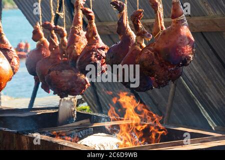 Des pattes de porc rôties au feu ouvert lors d'un festival gastronomique en Bretagne, en France, en été ensoleillé. Paysage marin en arrière-plan. Banque D'Images