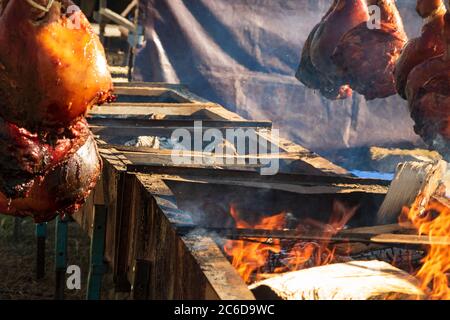 Des pattes de porc rôties au feu ouvert lors d'un festival gastronomique en Bretagne, en France, en été ensoleillé. Banque D'Images