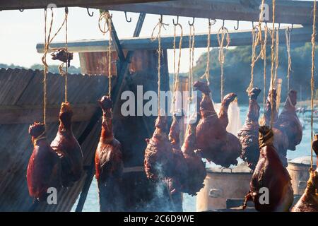 Des pattes de porc rôties au feu ouvert lors d'un festival gastronomique en Bretagne, en France, en été ensoleillé. Paysage marin en arrière-plan. Banque D'Images