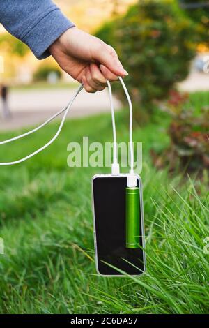 Une fille tient par câble un smartphone et une banque d'alimentation externe pendant la charge Banque D'Images