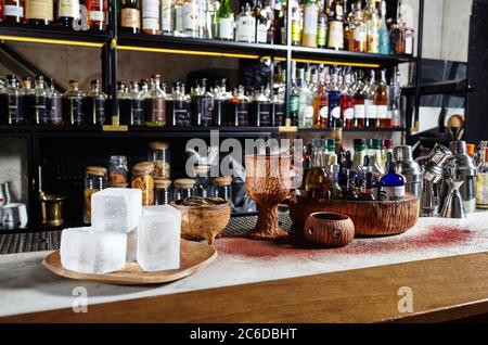 Ingrédients pour les cocktails en petites bouteilles.des shakers et des quartiers de citron sur le comptoir du bar. De grandes glaçons sur une assiette pour refroidir les boissons Banque D'Images