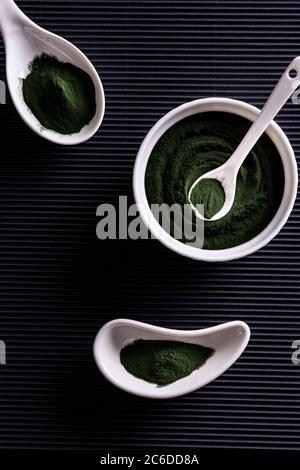 Poudre de chlorelle ou de spiruline vert naturel dans trois bols en porcelaine blanche de forme différente. Concept de nourriture saine et de régime. Élégant b Banque D'Images