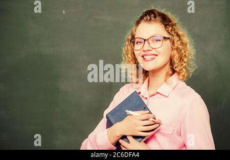 Enseignant meilleur ami des apprenants. Passionné de connaissance. La pédogue tient le livre et explique les informations. Concept d'éducation. Le professeur explique le sujet difficile. Professeur d'école de femme devant le tableau de surveillance. Banque D'Images