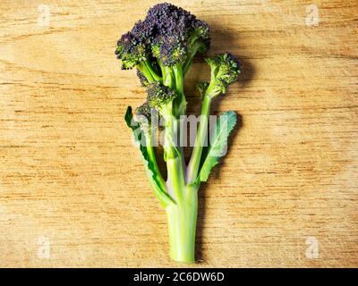 Une tige de brocoli pourpre au centre d'une planche à découper en bois Banque D'Images