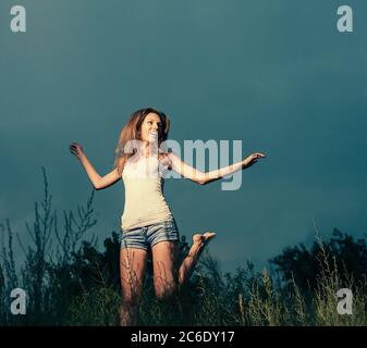 Jolly fille sautant et dansant dans la nuit. Image colorisée. Beaucoup d'espace de copie sur le ciel Banque D'Images