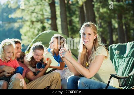 Famille souriante se détendre au camping dans les bois Banque D'Images