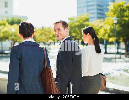 Homme d'affaires souriant marchant avec des collègues à l'extérieur Banque D'Images