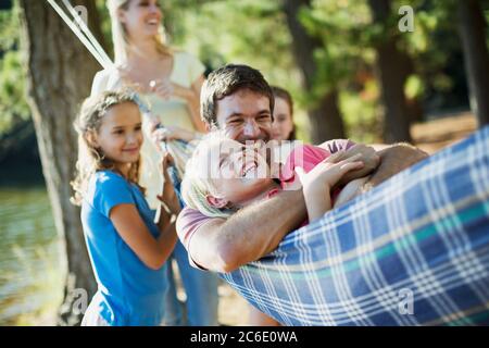 Bonne famille en train de poser dans un hamac en bois Banque D'Images