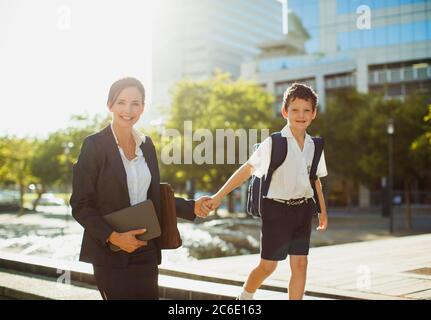 Femme d'affaires souriante marchant avec son fils à l'extérieur Banque D'Images