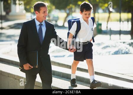 Homme d'affaires et fils tenant la main dans un parc urbain Banque D'Images