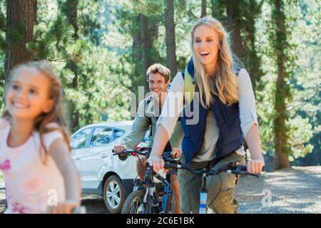 Famille souriante à vélo tout terrain dans les bois Banque D'Images