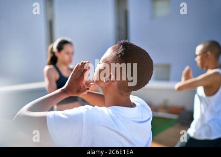 Sereine jeune femme pratiquant le yoga sur un balcon ensoleillé Banque D'Images