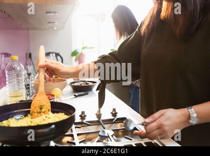 Femme cuisson du riz sur la cuisinière dans la cuisine Banque D'Images