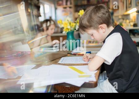 Boy doing homework at table à manger Banque D'Images