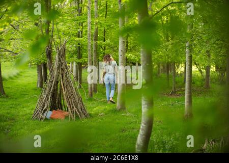 Femme près de la branche tipi dans la forêt Banque D'Images