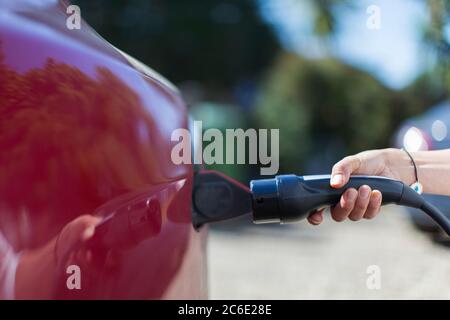 Femme en gros plan recharge la voiture électrique Banque D'Images