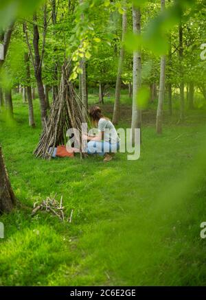 Femme faisant une tipi de branche dans les bois Banque D'Images