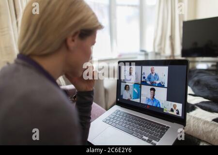 Femme discutant vidéo avec des médecins sur un ordinateur portable depuis la maison Banque D'Images