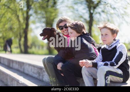 Bonne mère et fils avec chien dans un parc ensoleillé Banque D'Images