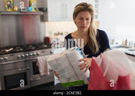 Femme déchargeant des produits d'épicerie dans la cuisine Banque D'Images