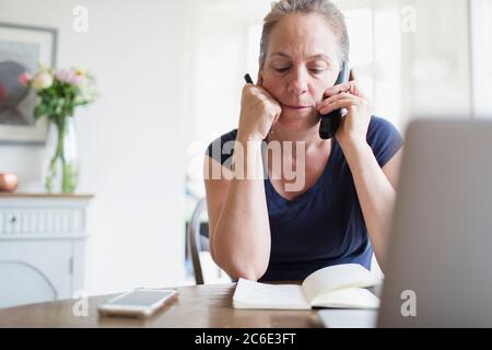 Femme travaillant à la maison parlant au téléphone Banque D'Images