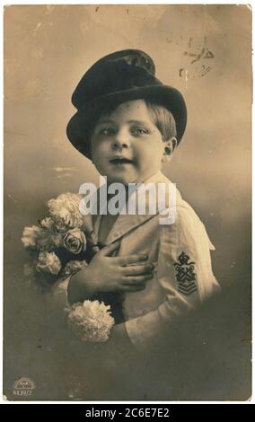 RUSSIE - VERS 1900 : carte postale rétro dépeint un garçon dans un chapeau de tête et avec un bouquet de fleurs. Photographie rétro teintée à la main Banque D'Images